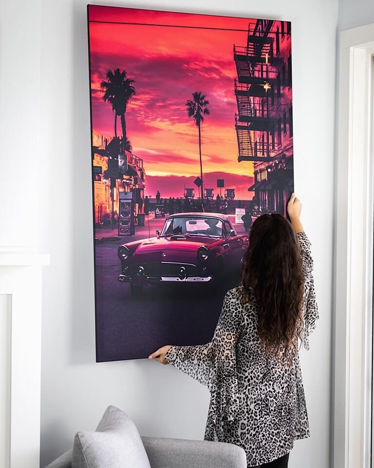 A model hanging a Classic Car wall art piece