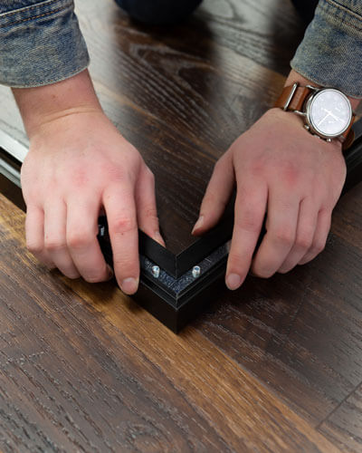 Hands putting together the frame of a wall art piece used to demonstrate some of the pros and cons of framed wall art