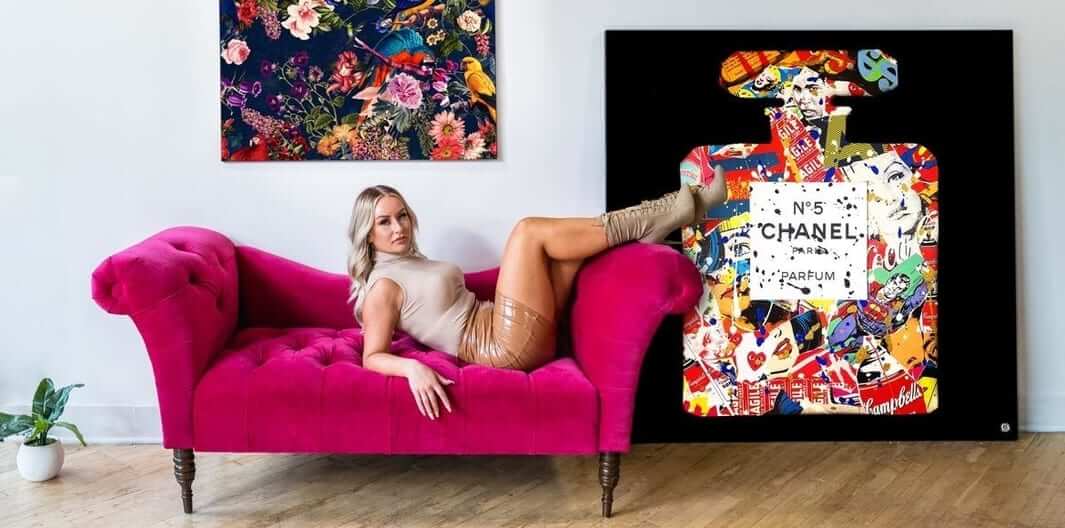 A model on a pink couch in front of a Chanel Number 5 fashionista wall art piece