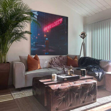 Large surreal art featuring astronaut and neon sign hangs above couch in living room.