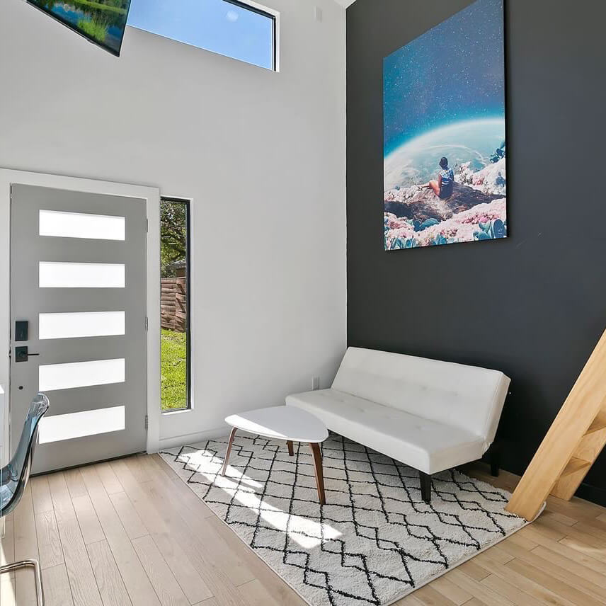 Massive surreal wall art of person looking out over another planet hangs on dark gray wall in open entryway