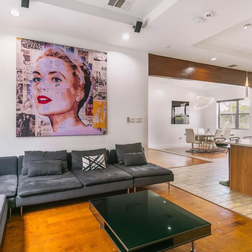 Extra large spray paint abstract wall art of Grace Kelly hung above gray couch in open living room