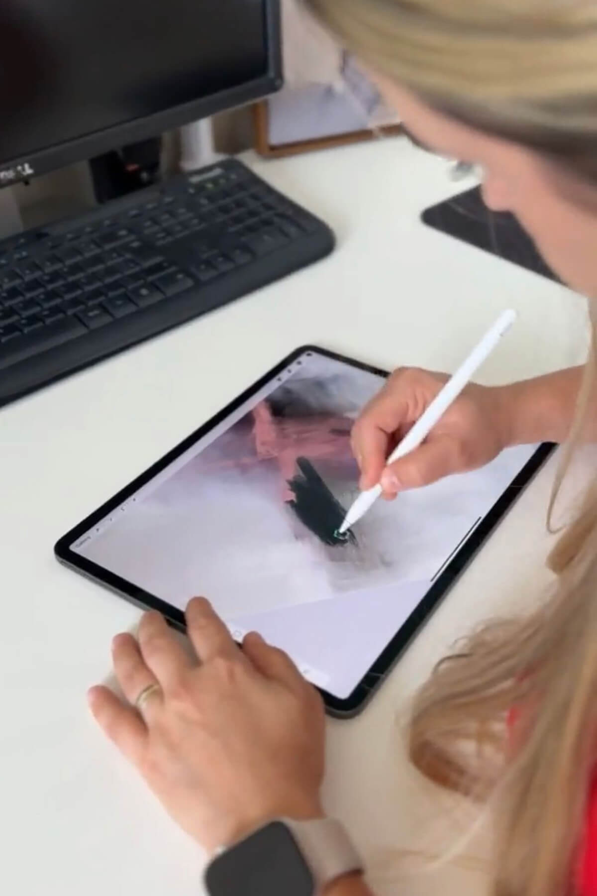 Artist Karine Tonial Grimm can be seen in her studio, using an iPad and white Apple Pen to create a piece of abstract art in dark teal. The viewer gets a glimpse into the artist's creative process as she works on the digital canvas, bringing her vision to life.
