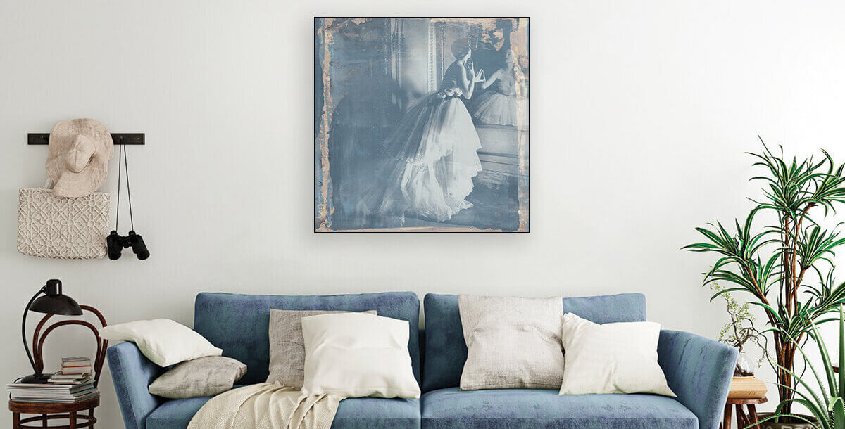 Large blue vintage wall decor of vintage woman dressed in large, layered dress with massive skirt hangs above blue velvet couch in eclectic boho living room.