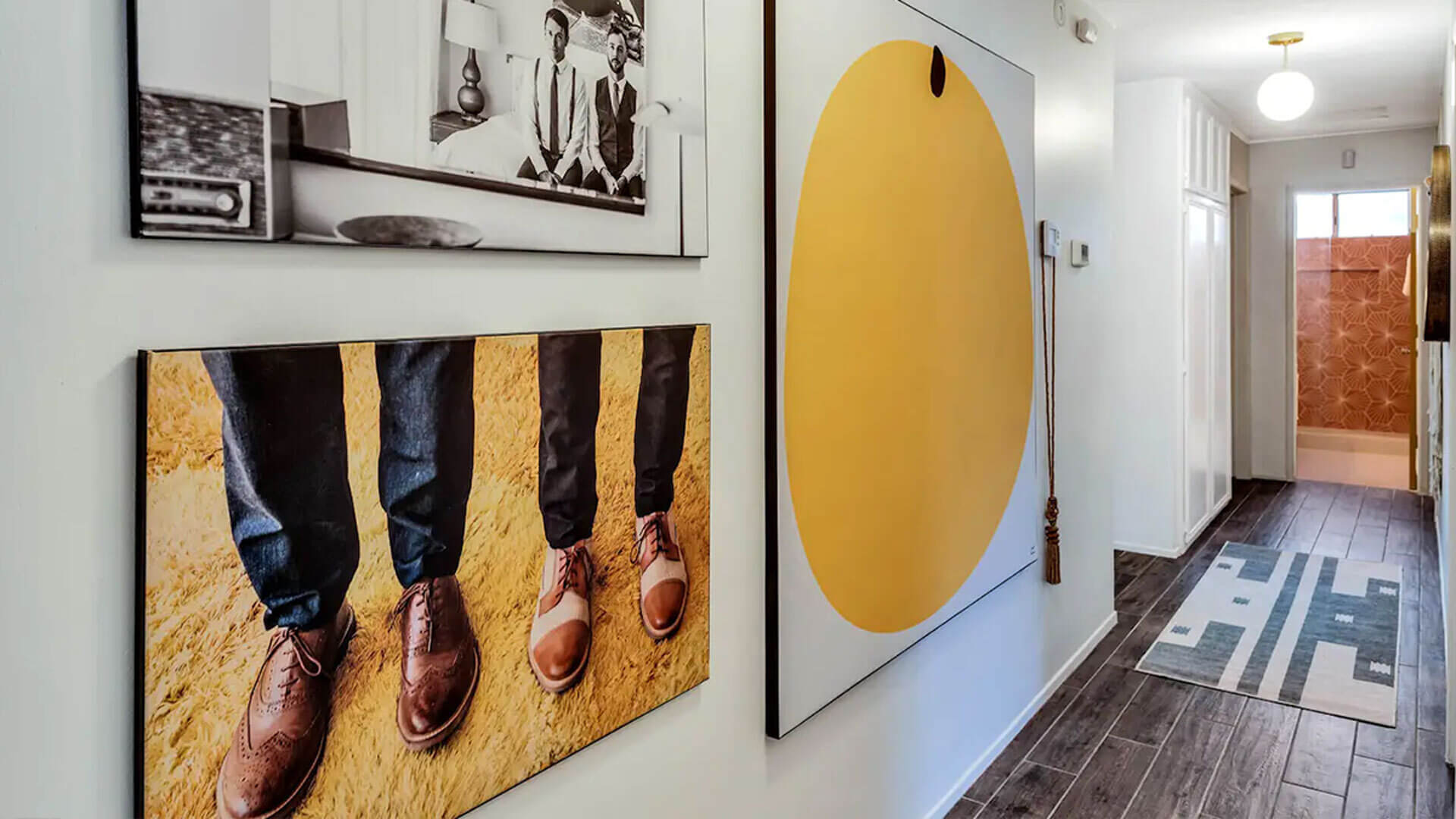 Large wall art set of three hangs on white wall in hallway.