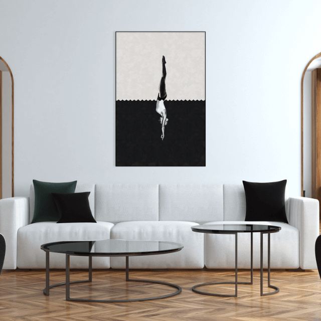Contemporary living room with a white sofa, black and green pillows, round glass coffee tables, and a black and white geometric artwork of a diver on the wall.