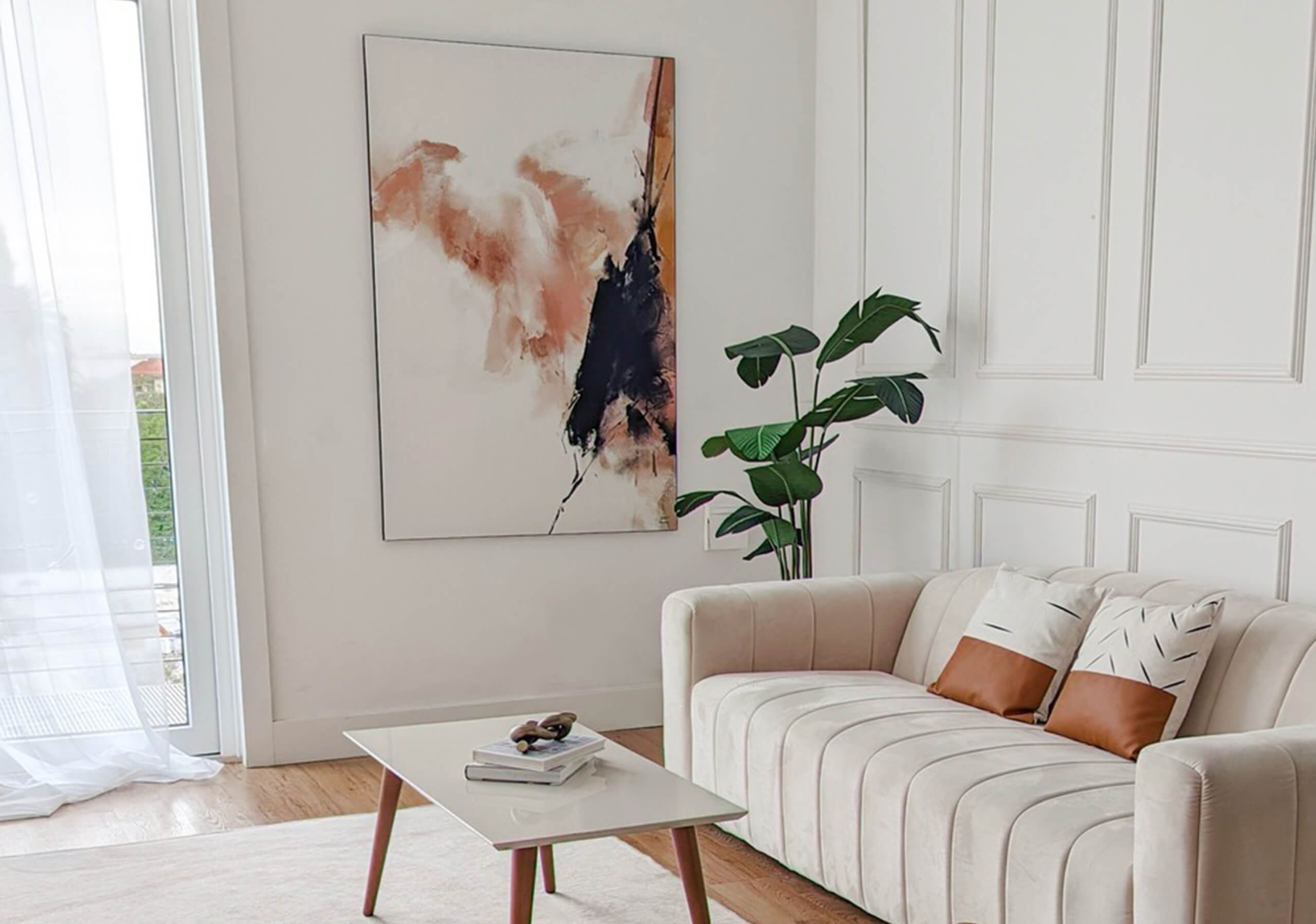 A well lit, clean white living area with neutral and earthy tones. Mostly beige, white, and some rusty browns and terra cotta colors in the image. The artwork hanging on the wall is a BIG Wall Decor large wall art piece made by Artur Chen. The artwork is an abstract wall art print with terra cotta colors, rusty brown and black.