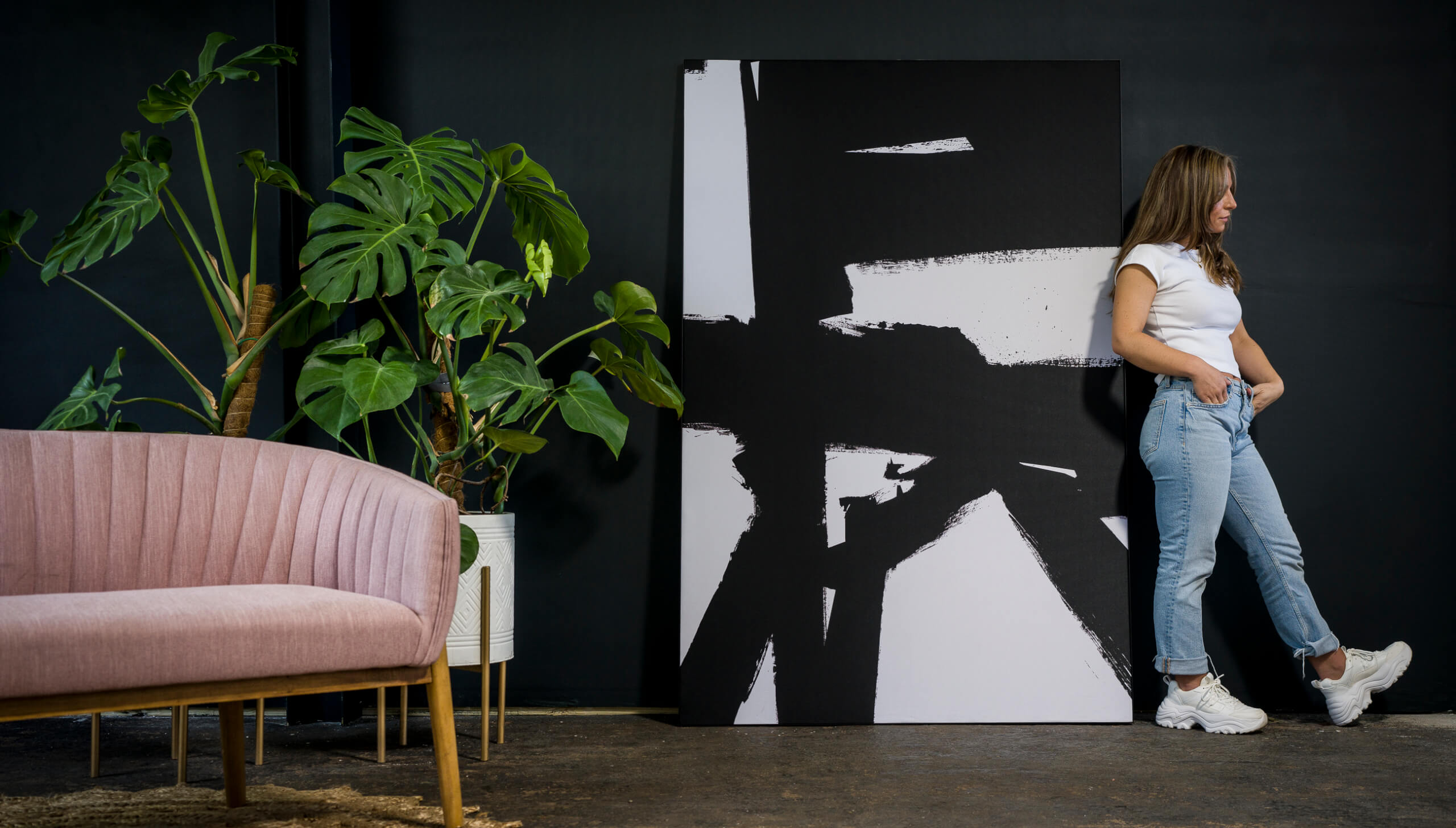 Girl standing next to giant black and white abstract wall art print, The artwork is more han 5 feet tall. The monochrome wall art is the highlight of the image.