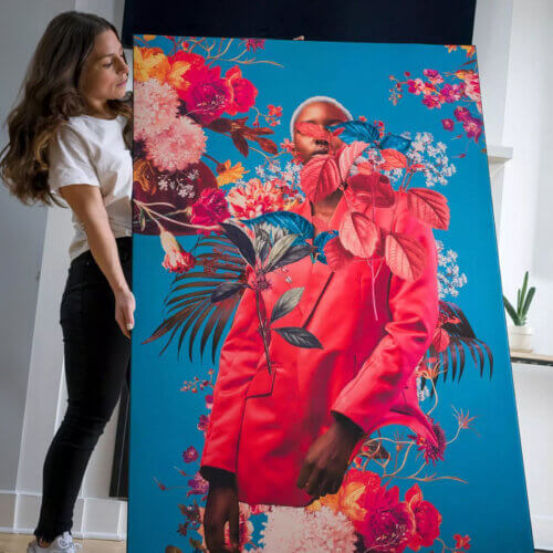 A woman holding a large, vibrant art print against a wall.