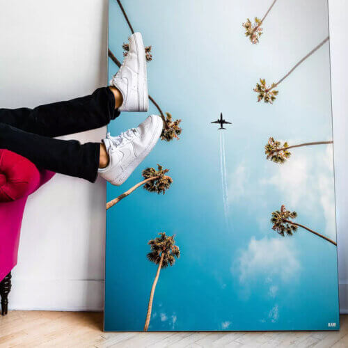 A large palm tree art print leaning against a wall with legs resting on it.
