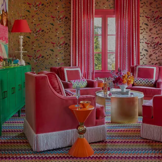 Vibrant Dopamine Decor living room with pink velvet chairs, gold tables, and colorful patterns, representing 2025 design trends.