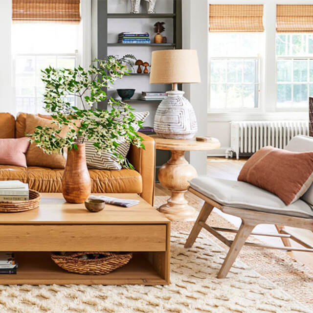 Living Room with warm and cozy leather sectional, textured rug, wood coffee table, and layered décor accents