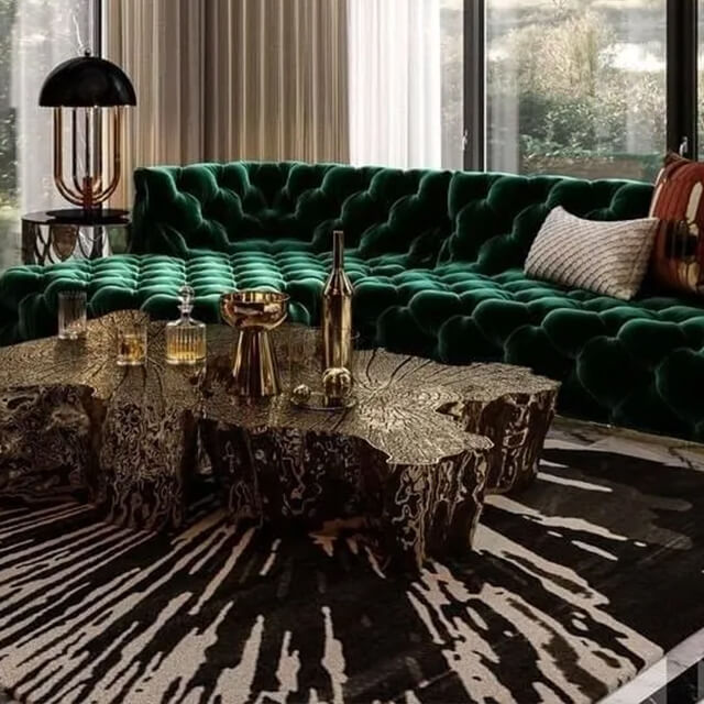 Glamorous living room with green velvet sectional, metallic accents, and rich textures, embodying the Loud Luxury interior style.