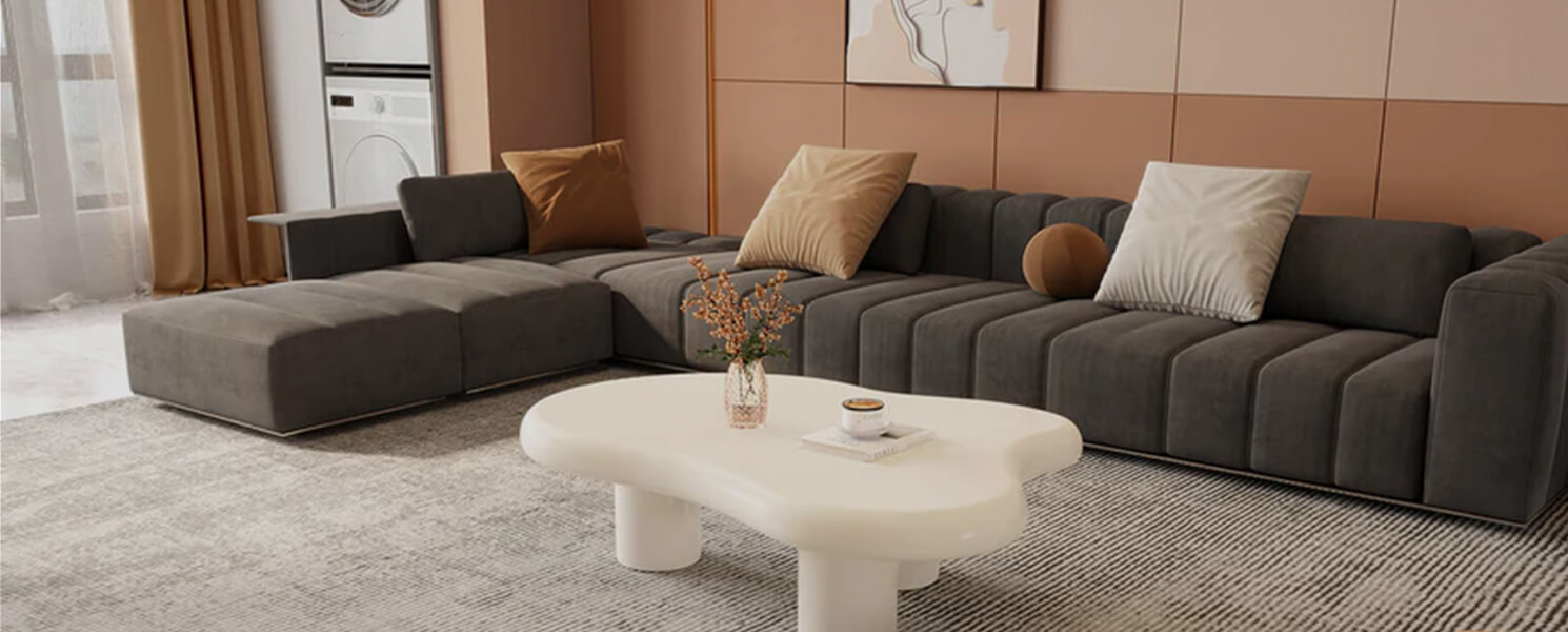 Modern modular living room with curved white coffee table, gray velvet sectional, and soft brown accent wall panels.