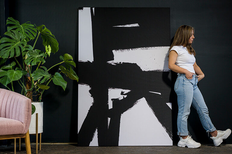oman standing next to oversized black and white abstract wall art in a modern interior