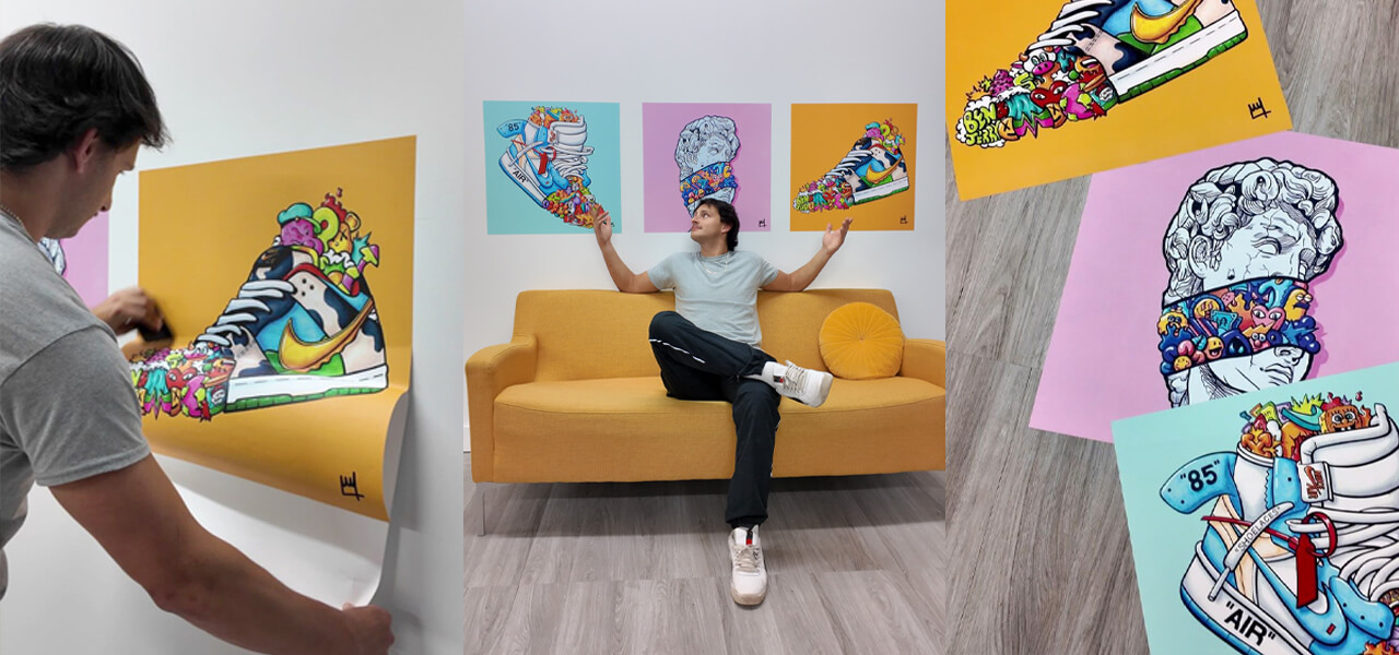 Guy hanging three bright sneaker prints above a yellow couch in a dorm room