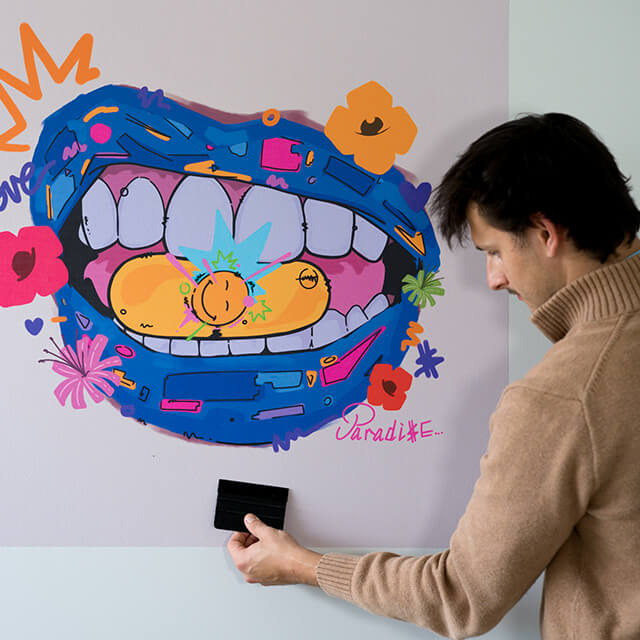 Man installing a peel and stick art print on a dorm wall with a squeegee
