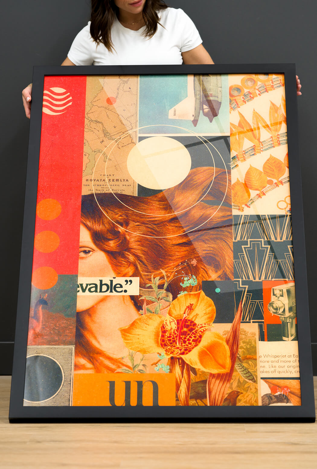 Young woman posing behind a large acrylic print featuring a vintage collage design with a glossy reflective surface.