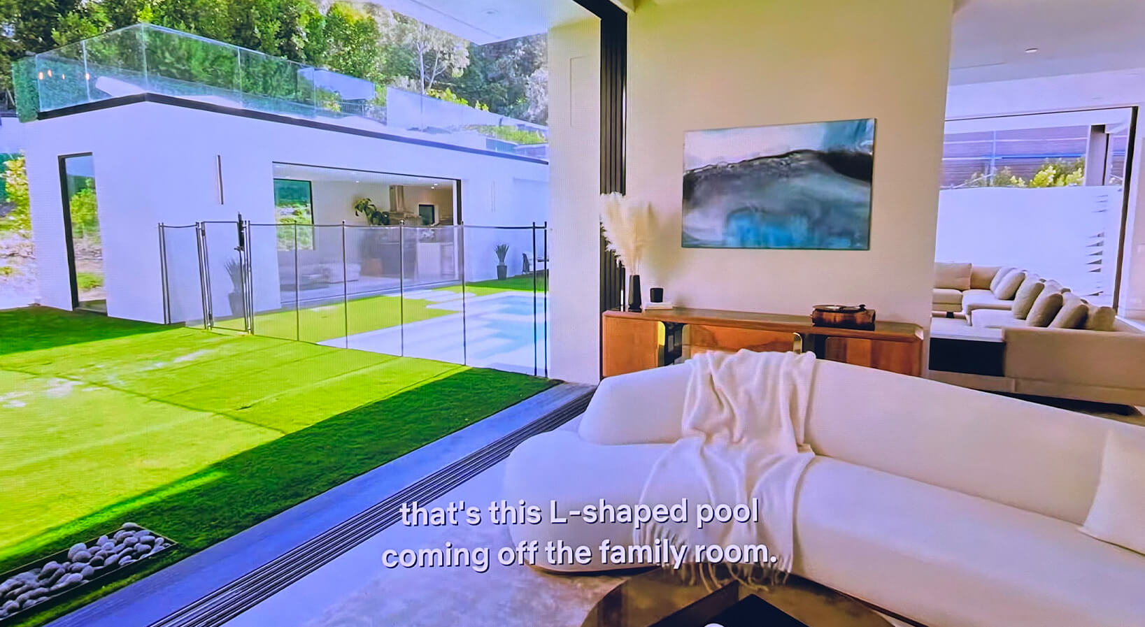 Large modern wall art in an open-concept luxury home with indoor-outdoor living and views to the backyard.