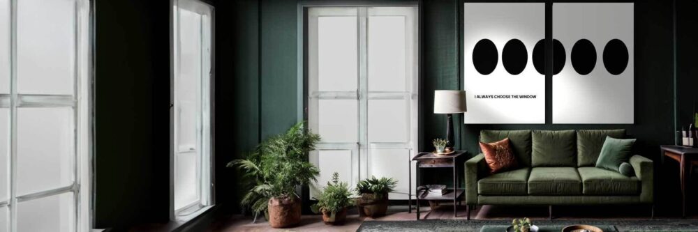 Horizontal view of a large dark green room with hardwood floors. To the right is a long green couch accompanied by an end table and lamp. Above the couch is the focal point, a two piece set of artwork by George Rosaly that goes together. The artwork is a minimal style white background. The artwork is split into two prints, the left print has a phrase and 2 and a half dots. The second print has the other half of the 2 and a half dots.