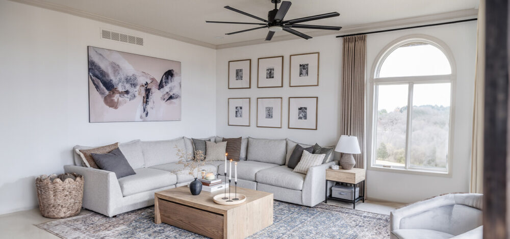 A modern living room featuring a large abstract painting above a sectional sofa and a gallery wall of six framed photos, illustrating how to choose the right wall art size.