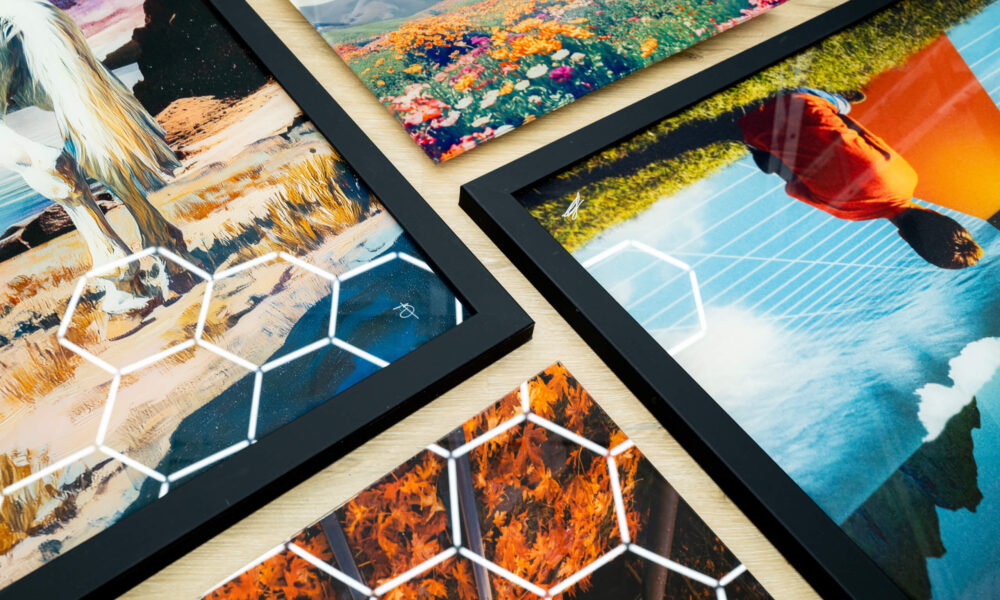 Close-up of multiple infused acrylic wall art prints with black frames, featuring vibrant artwork including a horse, colorful flowers, autumn leaves, and a surreal portrait with geometric reflections on the glossy surface.