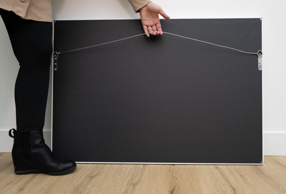 Person holding hanging wire on the back of a framed acrylic wall art, showing how to hang artwork with D-rings and wire.