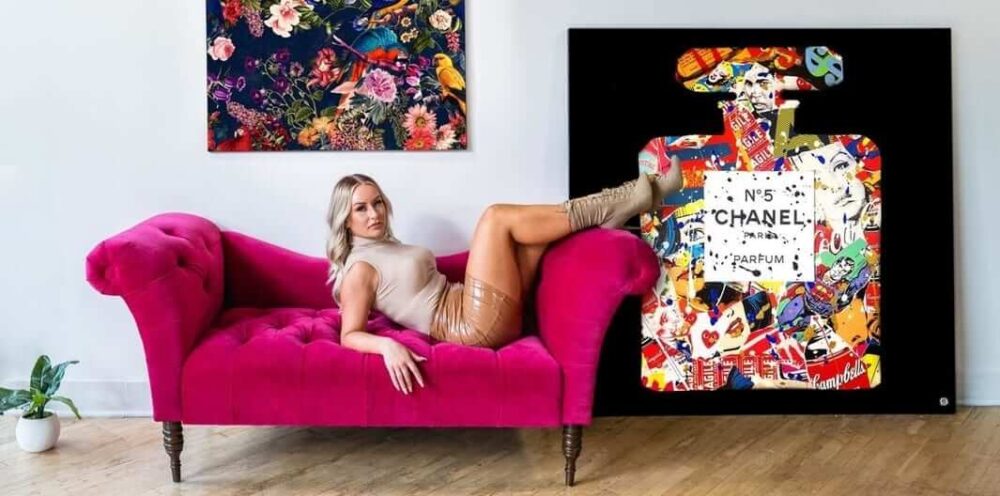 A model on a pink couch in front of a Chanel Number 5 fashionista wall art piece