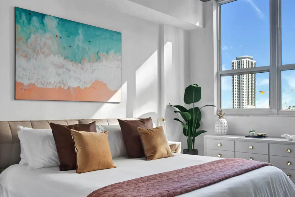 Extra large aerial beach coast photo hung above bed in neutral apartment