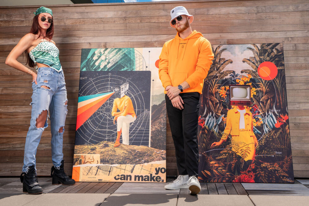 Massive surreal artwork featuring people with old projectors and tv's instead of heads leans up against a wooden wall with a couple standing next to them.