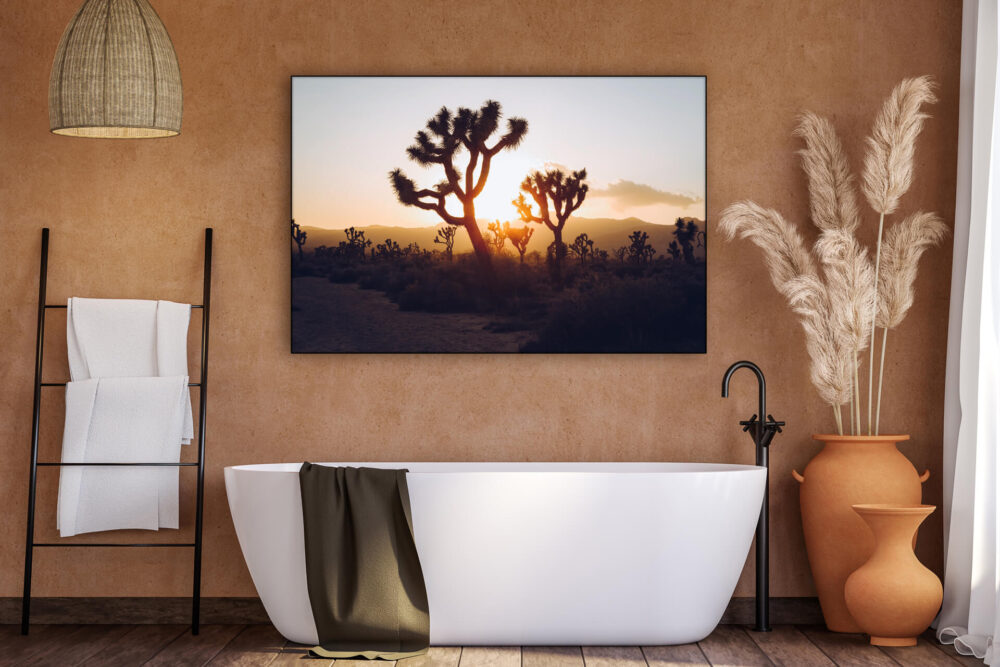 Massive bathroom wall art featuring sunrise photo at Joshua Tree National Forest hangs in warm modern bathroom above soaking tub.