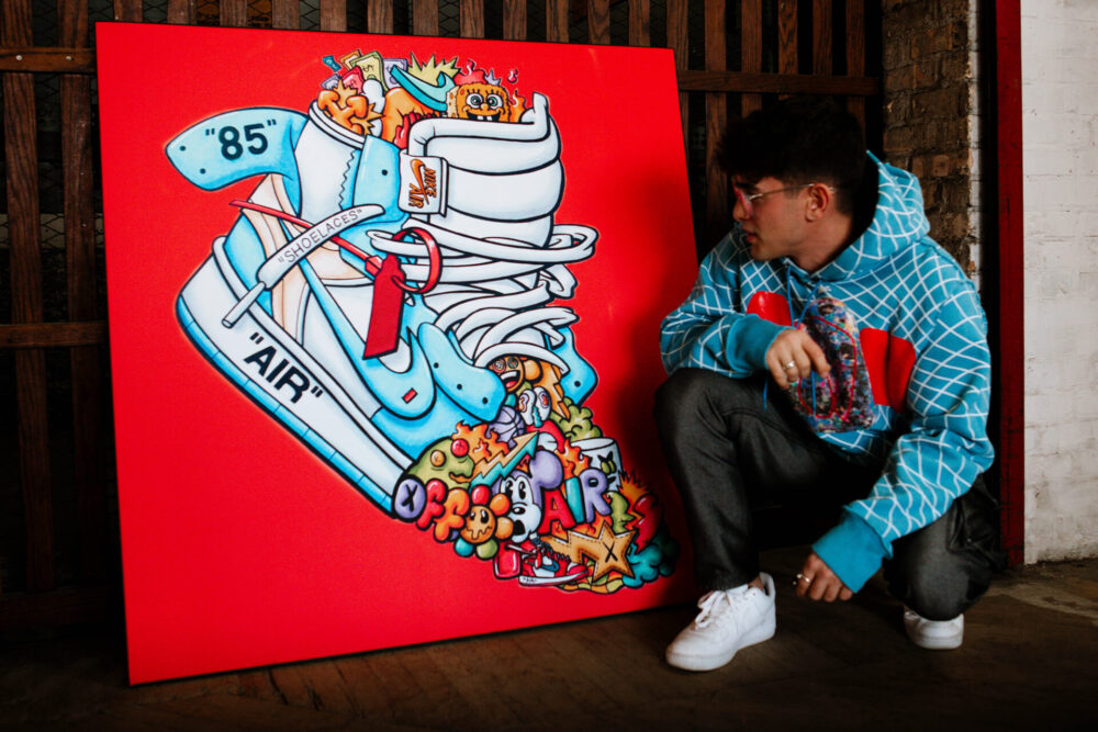 Cartoon drawing of light blue Air Nike Sneakers on a red background leans up against a wall as a man in a light blue sweatshirt crouches in front of it.
