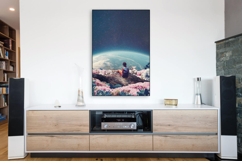 Surreal wall art featuring woman sitting in a field of flowers and looking out over Earth hangs above record player and entertainment center in modern living room.