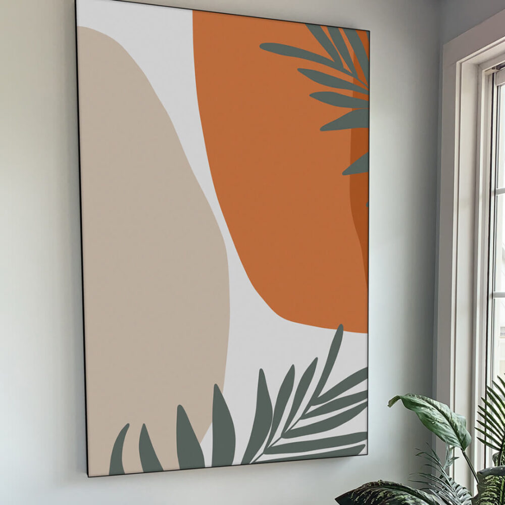 Extra large orange and tan abstract art with sage green tropical leaves hangs on white living room wall.