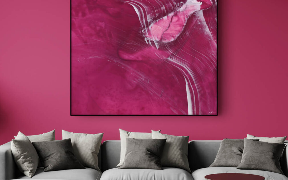 Living room with powerful accent wall in Viva Magenta features abstract magenta painting hanging above light grey couch.