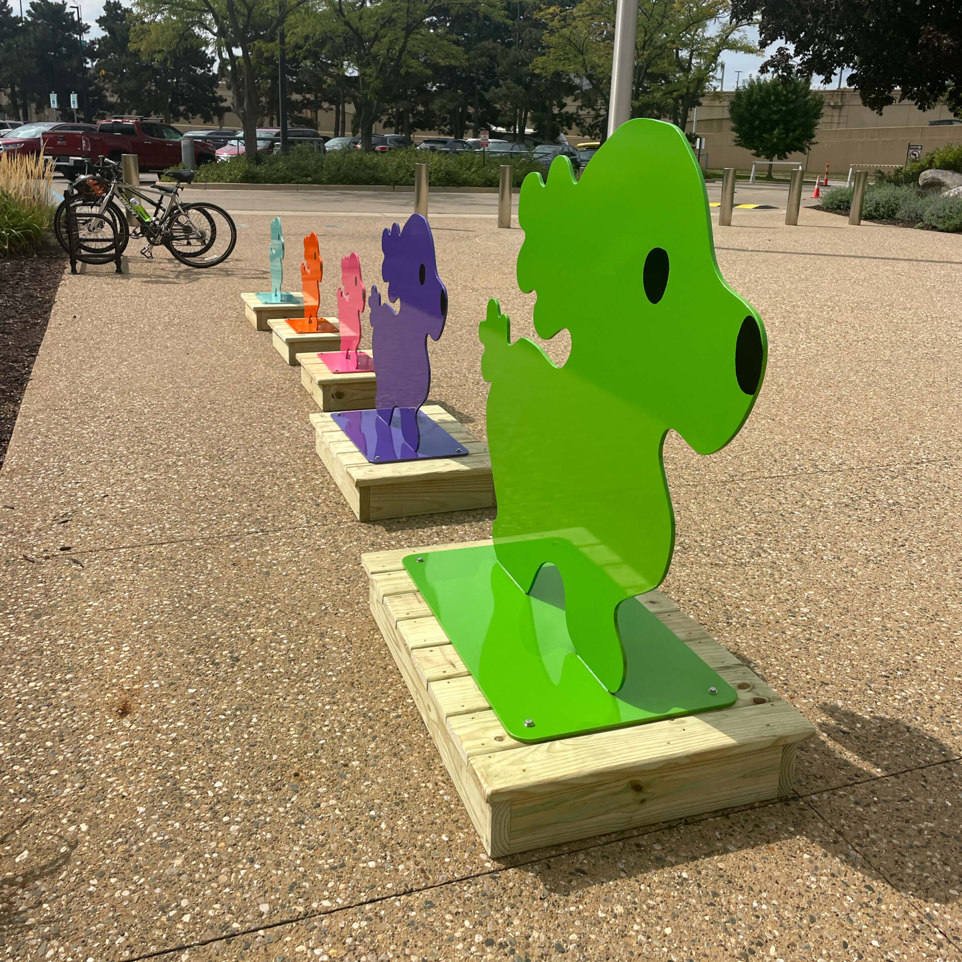 Large row of dog cut outs that resemble Snoopy in vibrant colors on display on sidewalk.