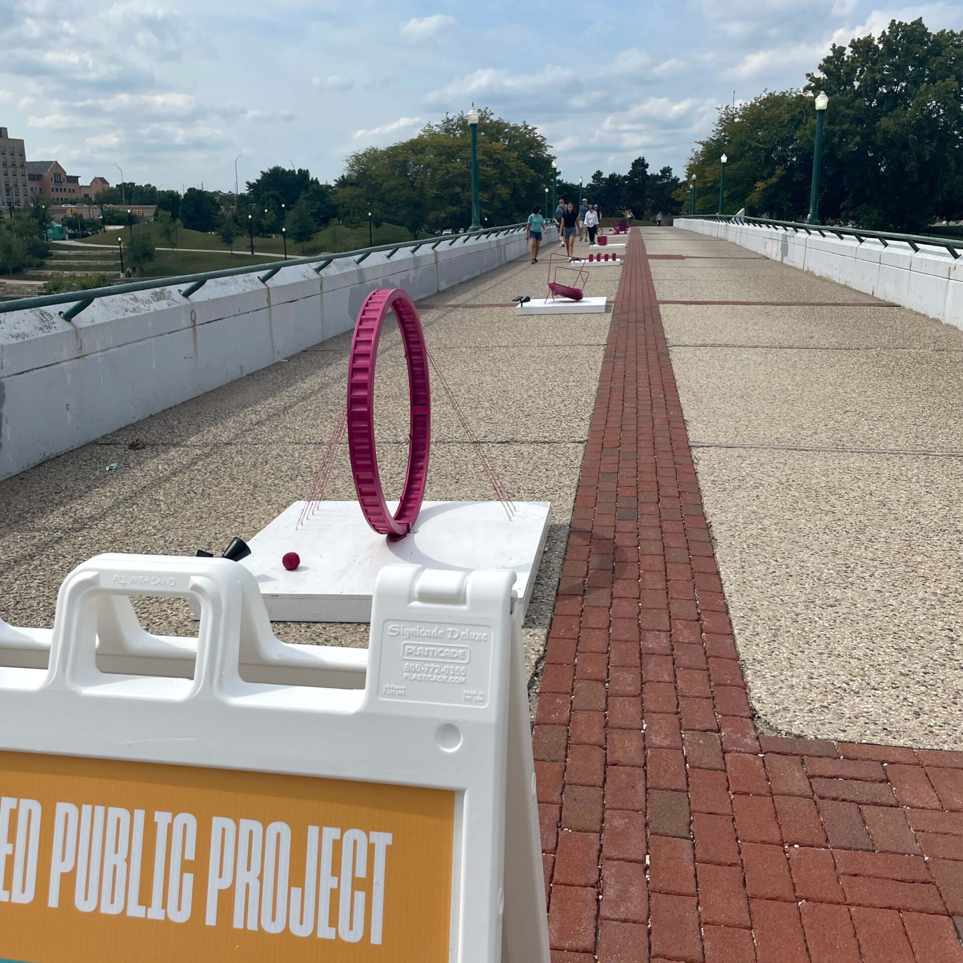 Pedestrian footbridge the Gillett Bridge in Grand Rapids has series of pink metal structures scattered across for the featured public project