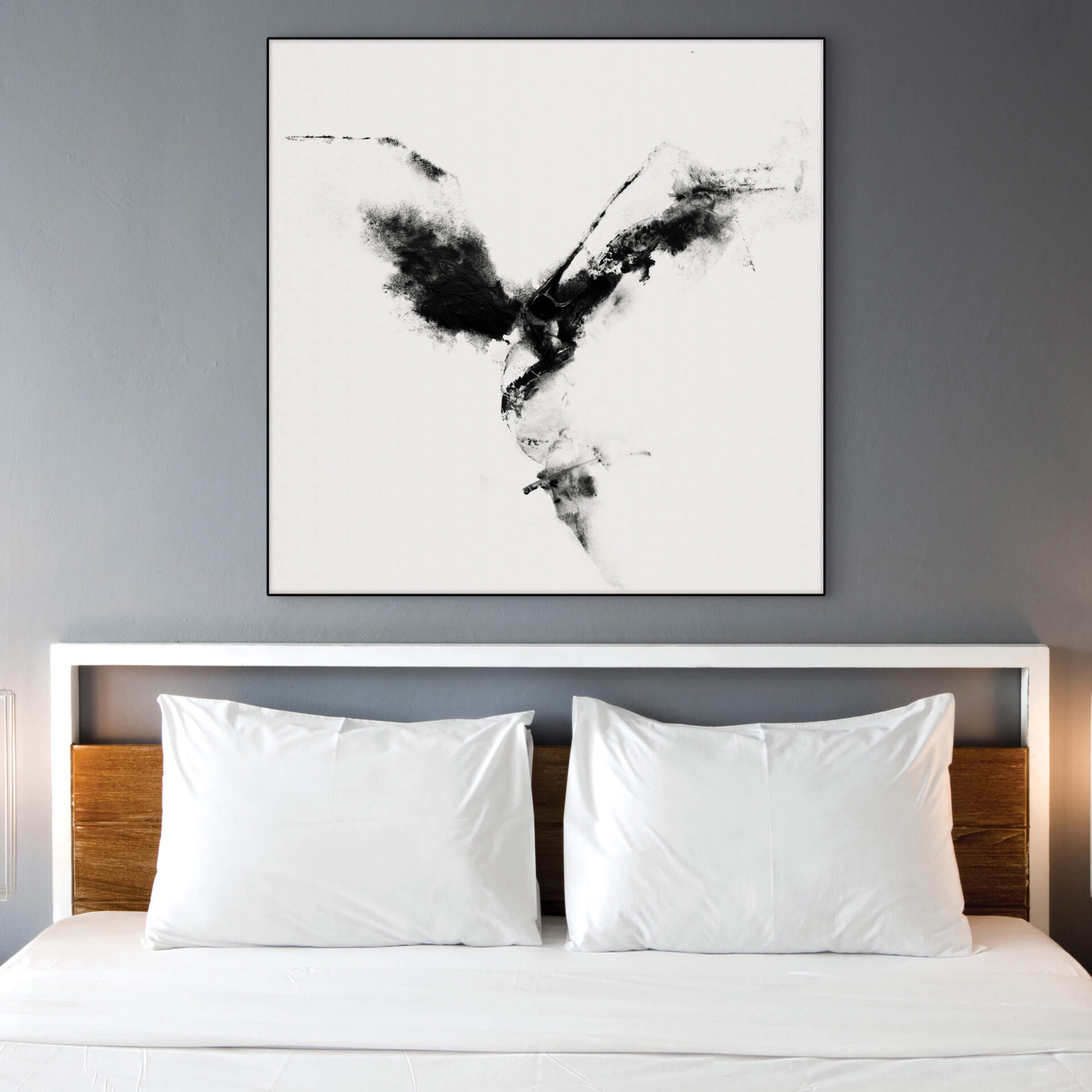 Extra large black and white abstract wall art hangs above white bed on light gray wall.