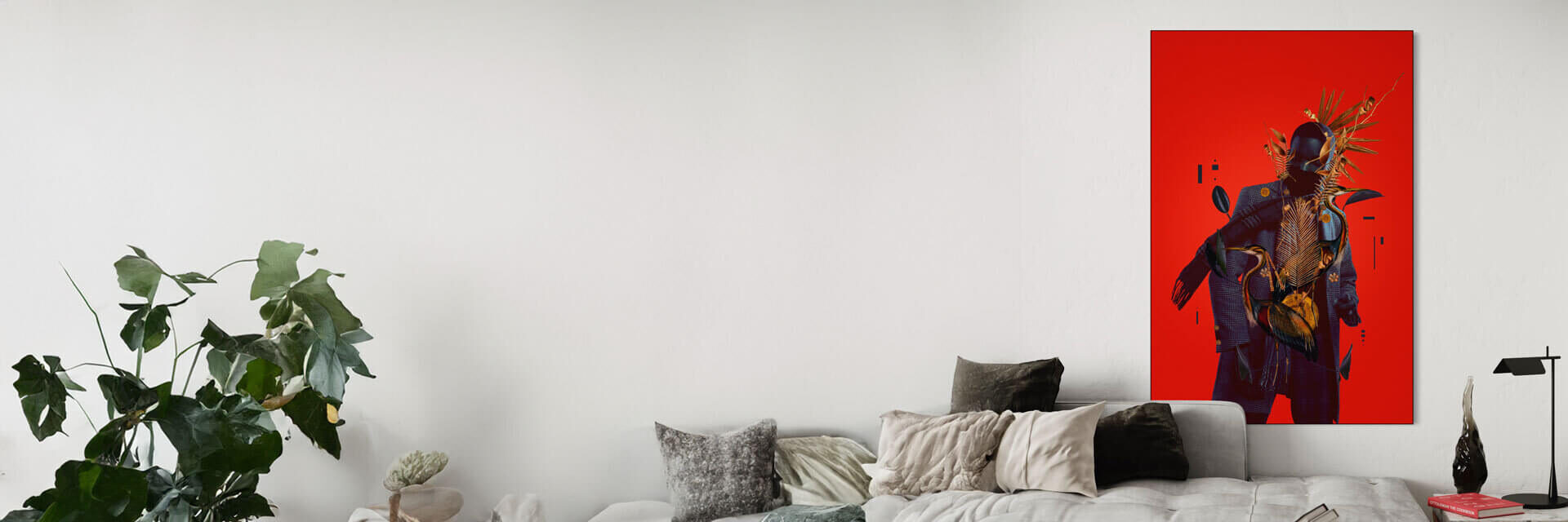 Neutral/white room with neutral and white furniture including a white couch with white and grey pillows. To the left is a green house plant and to the right is a bedside table with a small lamp and a bright red colored book. On the wall you can see a bright red piece of BIG Wall Decor artwork on the wall. The artwork is a bright and vivid red.