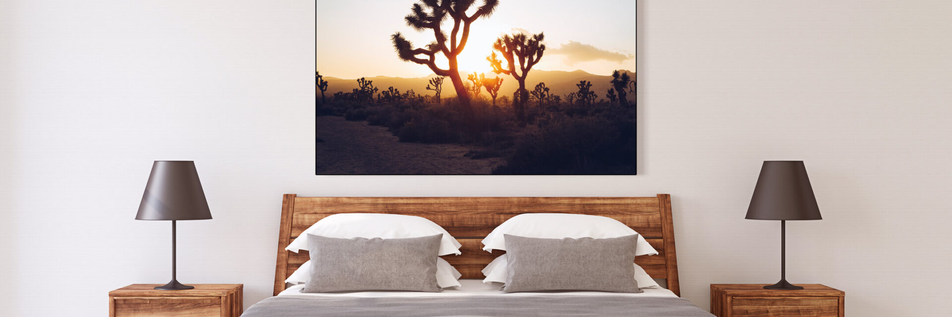 Landscape photo of Joshua Tree forest at sunrise hangs above the bed in neutral bedroom.