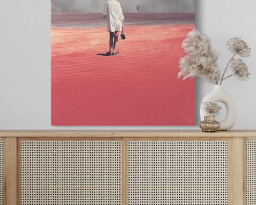 Huge pink surreal artwork of woman in pink sand desert looking at man in distant storm of clouds hangs on white wall in modern boho living room