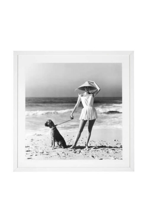 Black and white art print of a vintage-style girl walking a dog on the beach, shown on a white background.