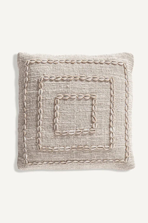 Seashell accent pillow in neutral tones on a white background.