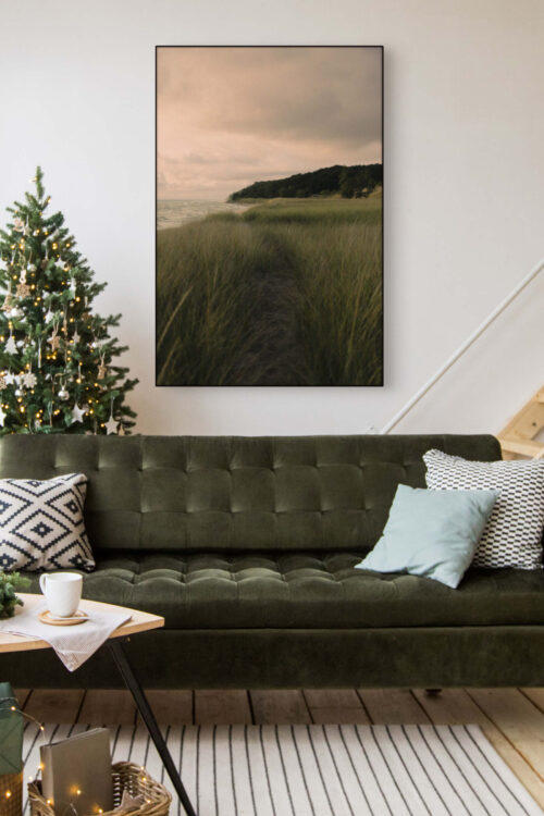 Oversized nature landscape photo of Lake Michigan hangs above dark green velvet modern couch next to neutrally decorated Christmas tree.