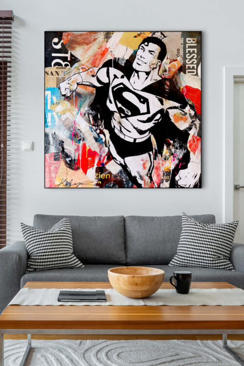 Large colorful Superman wall art collage hangs on white wall above light grey couch in modern living room.