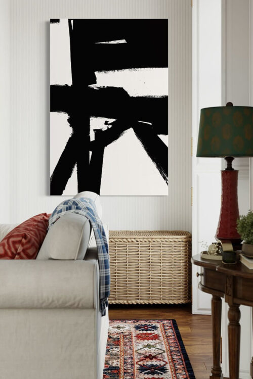 Massive black and white abstract painting hangs on white wall above wicker basket and white couch in living room.