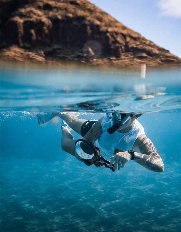 A female artist, Jessica Loiterton, swims underwater in the ocean in Hawaii, while snorkeling and taking underwater photos