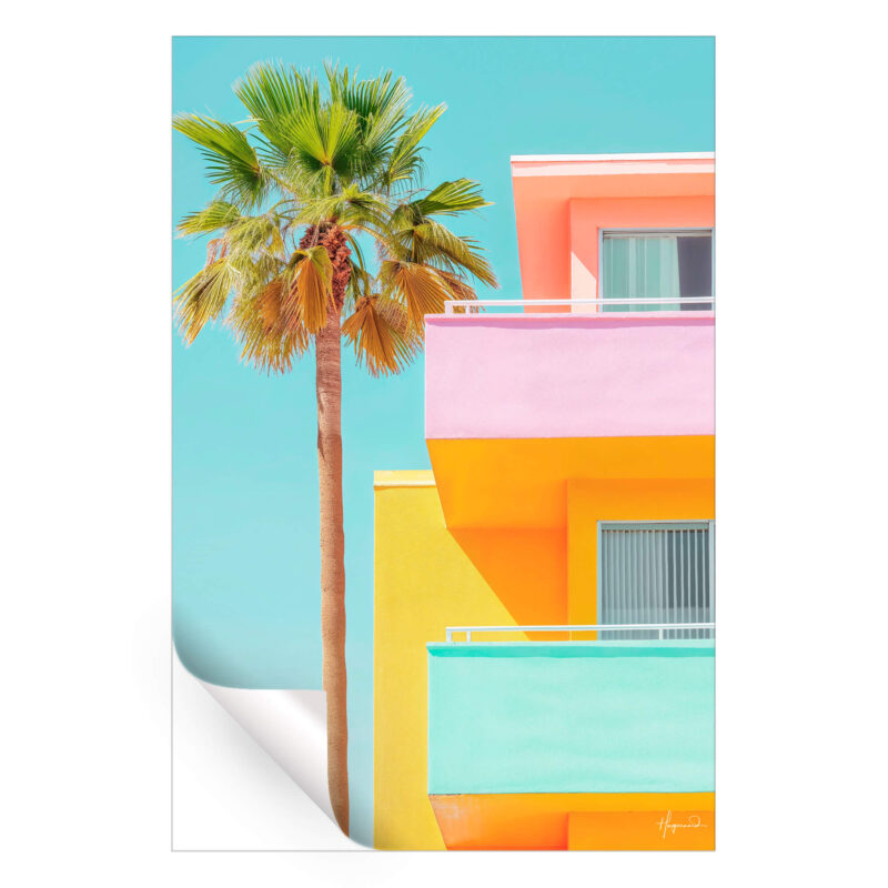 Vibrant building with pink, yellow, and turquoise colors, complemented by a tall palm tree, against a blue sky.