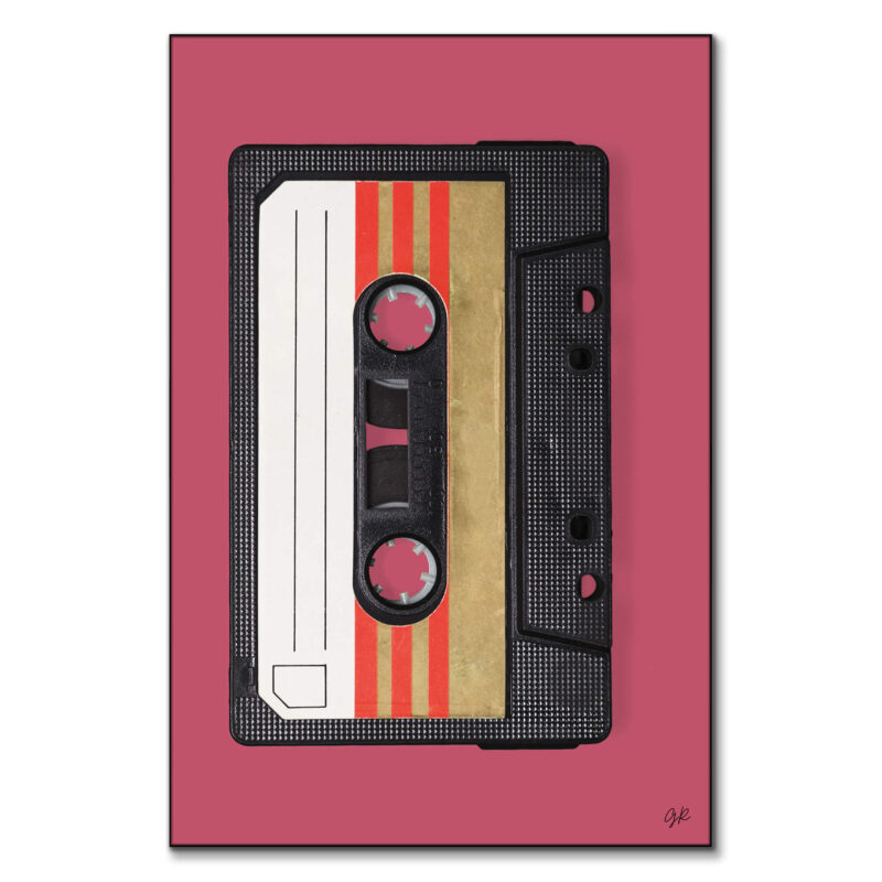 Close-up of a vintage black audio cassette tape with retro gold and red stripes on the label against a muted pink background.