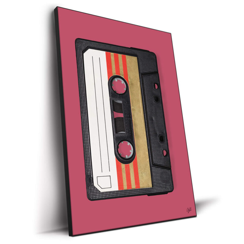 Retro black audio cassette tape with gold and red stripes on the label against a dark pink background.